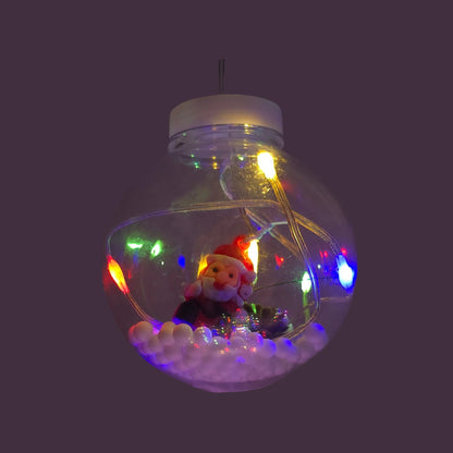 Foco decorativo navideño colgante transparente con figura de Santa Claus, base nevada y luces LED multicolores vibrantes.