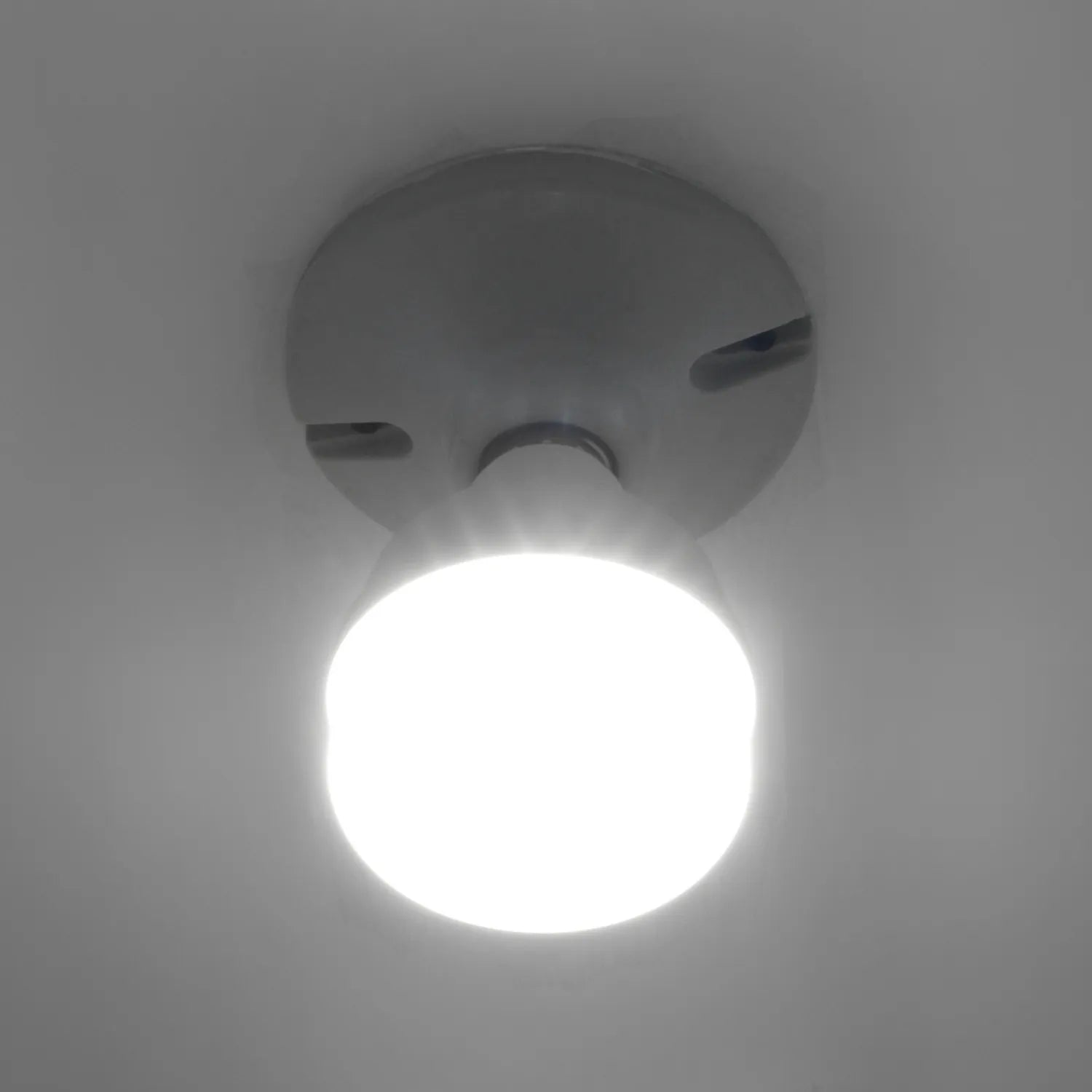 Foco LED blanco encendido en portalámparas de techo gris para iluminación interior eficiente