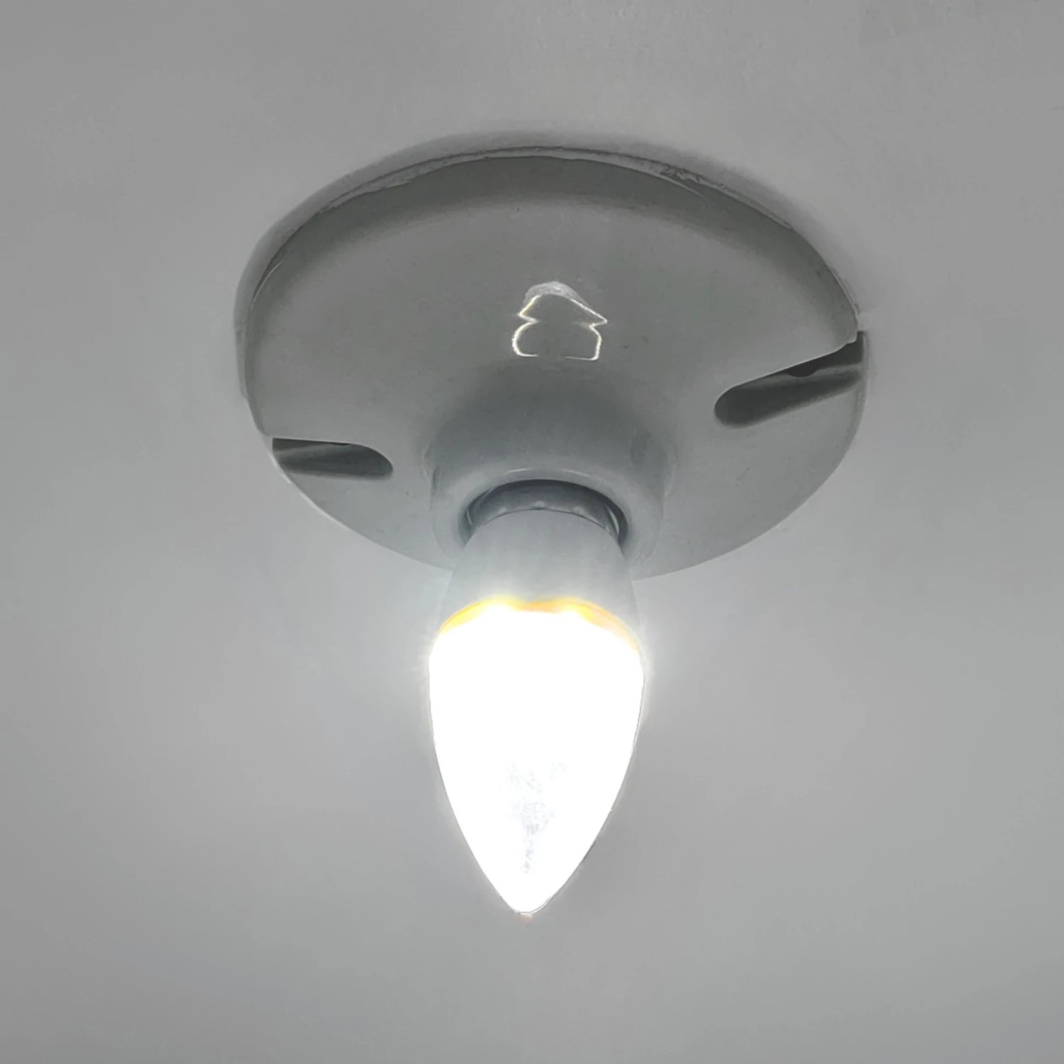 Foco LED tipo vela 4W encendido, con base roscada, emite luz fría brillante.