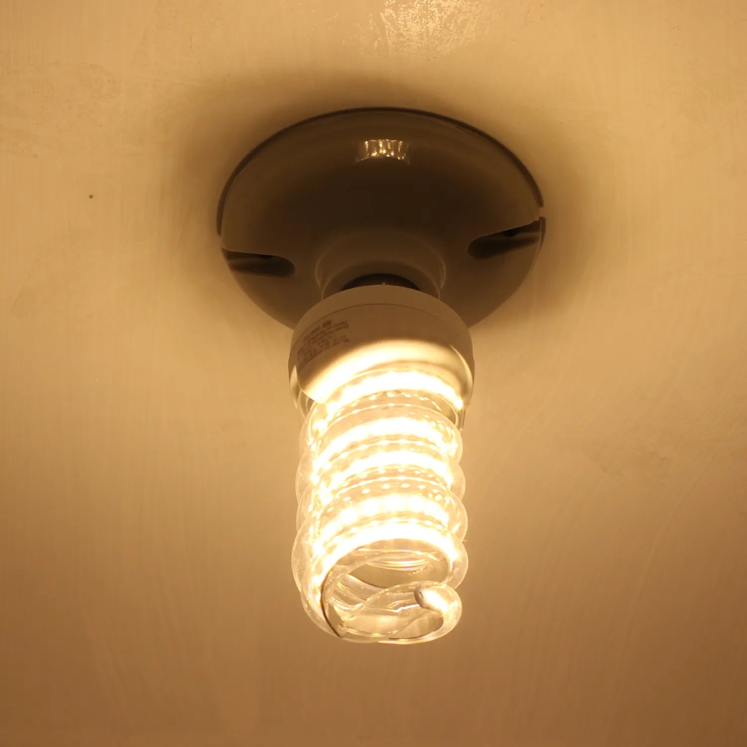 Bombilla ahorradora tipo espiral luz cálida encendida en portalámparas de techo para iluminación de interiores